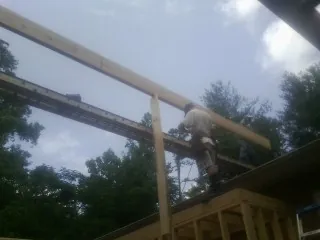 Carpenter setting a ridge beam over a new addition frame — Ice Dam Removal by Roofing Brothers in Mayodan
