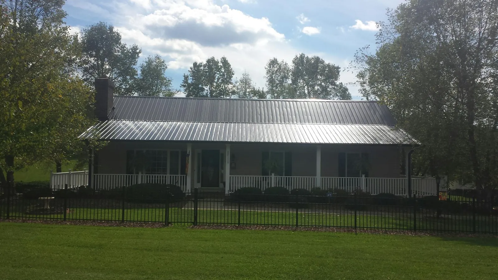 Gray metal roof on a brick ranch with a full width front porch — Gutter Guard Installation work by our crew in Mayodan