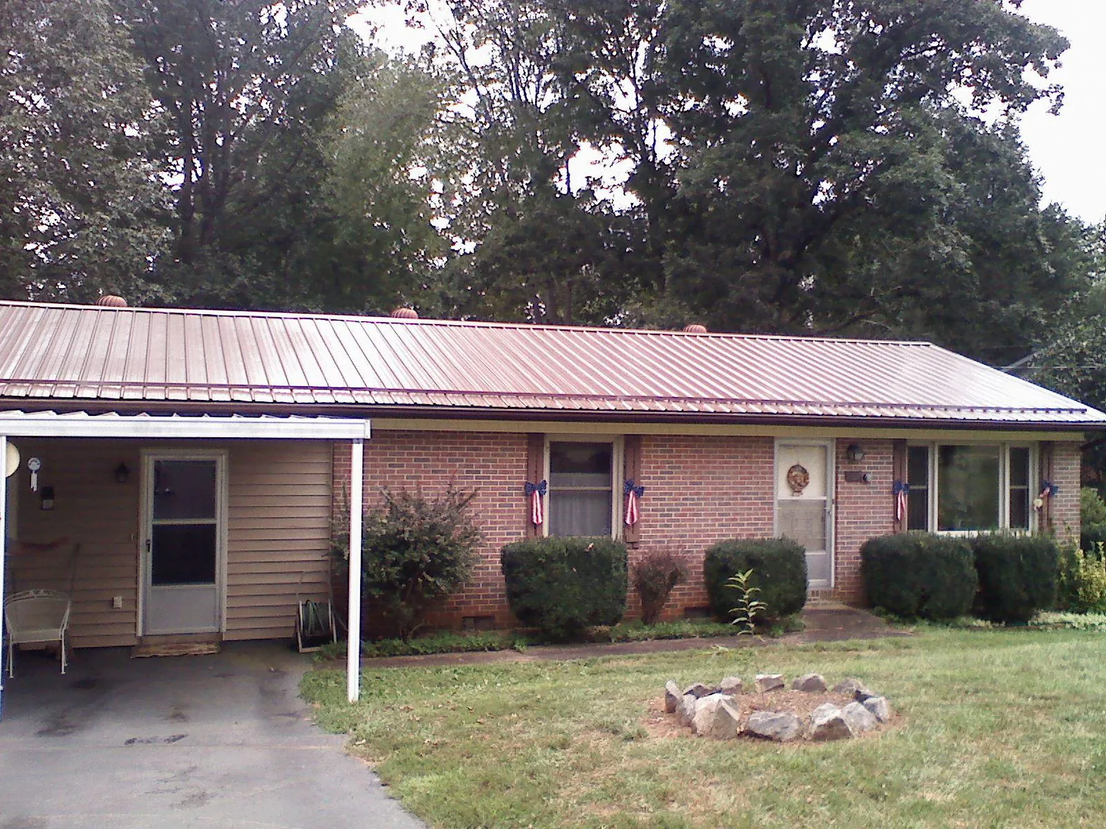 Bronze metal roof and carport on a brick ranch home — Roof Repair work by our crew in Mayodan